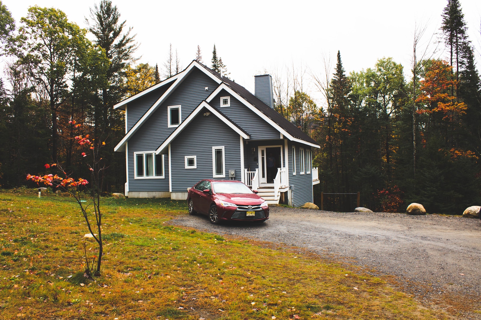 red car parked beside white wooden house