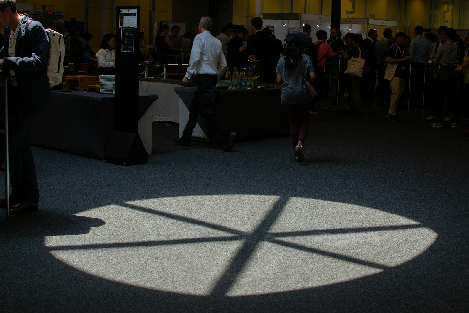 People walk near a spotlight on the floor.